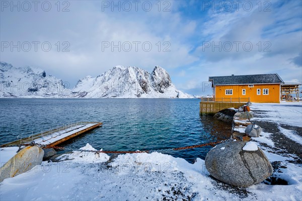 Yellow traditional rorbu house in Sakrisoy fishing village in norwegian fjord in winter on Lofoten Islands