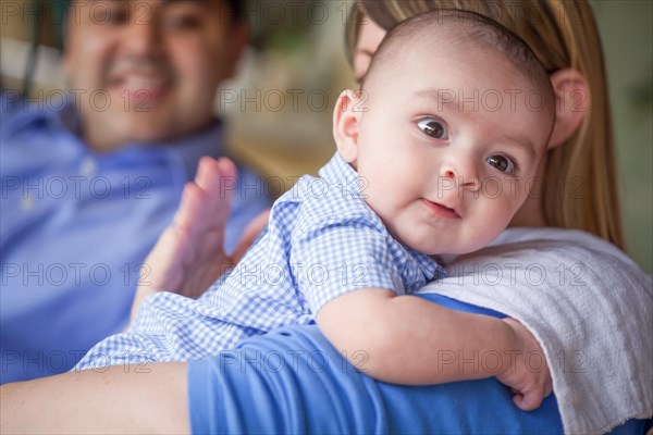 Happy attractive mixed-race couple burping their son