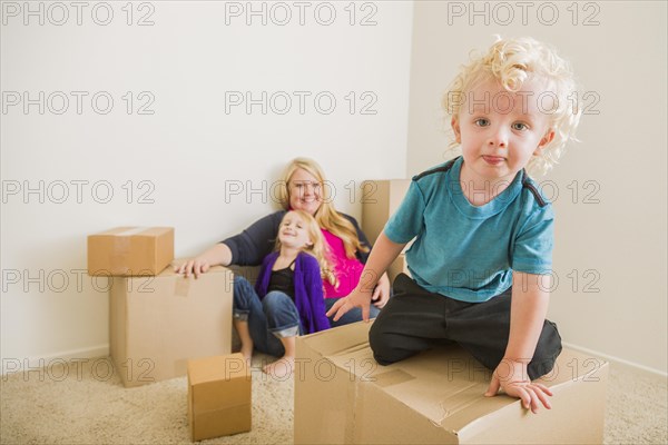 Playful young family in empty room playing with moving boxes