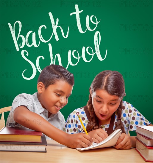 Back to school written on chalk board behind hispanic boy and girl having fun studying together