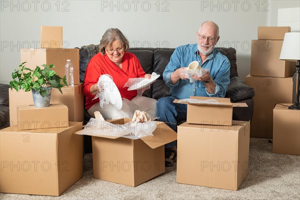 Senior adult couple packing or unpacking moving boxes