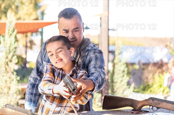 mixed-race father and son at fairground shooting range