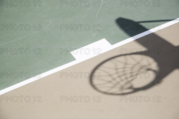 Abstract shadow of basketball hoop and net against court surface