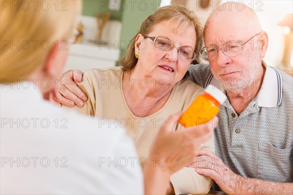 Doctor or nurse explaining prescription medicine to senior adult couple