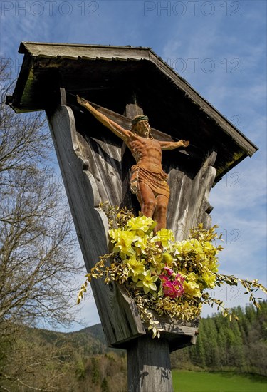 Geschnitztes Wegkreuz mit Blumenschmuck