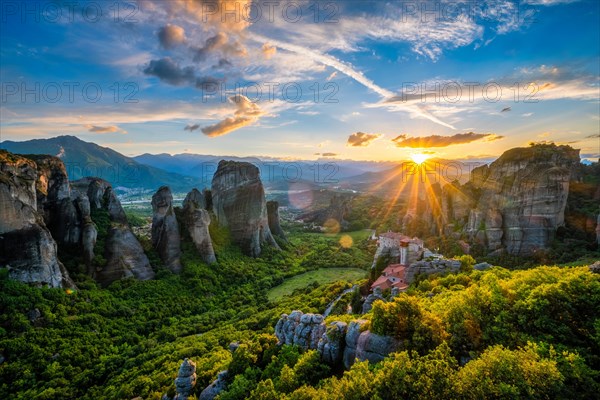 Sunset over monastery of Rousanou and Monastery of St. Nicholas Anapavsa in famous greek tourist destination Meteora in Greece on sunset with sun rays and lens flare