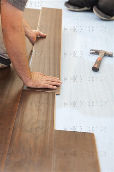 Man installing new laminate wood flooring abstract