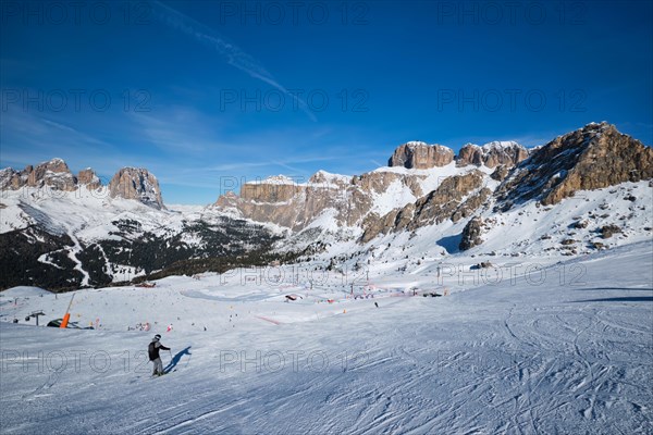 View of a ski resort piste with people skiing in Dolomites in Italy