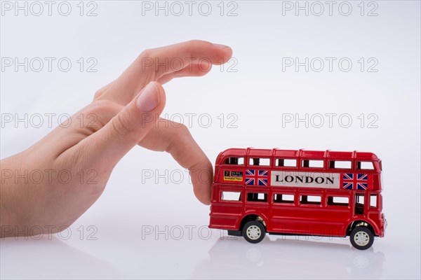 Child hand playing with London double decker bus model on white background