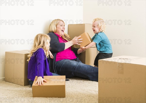 Playful young family in empty room playing with moving boxes