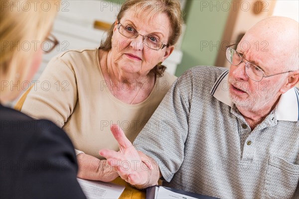 Senior adult couple going over documents in their home with agent at signing