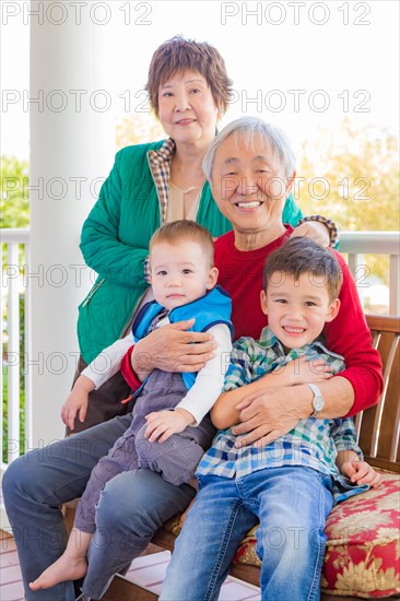 Senior adult chinese couple sitting with their mixed-race grandchildren