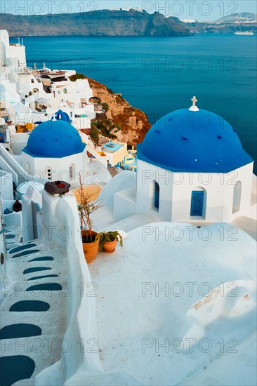Famous view from viewpoint of Santorini Oia village with blue dome of whitewashed greek orthodox Christian church of traditional greek architecture