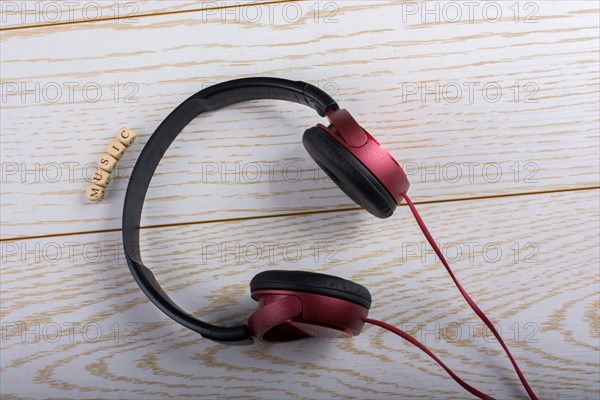 Dice-sized alphabet cubes spelling music and red headphones on wooden background