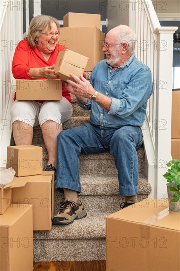 Senior couple resting on stairs surrounded by moving boxes