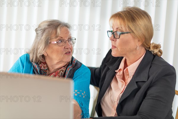 Woman helping senior adult lady on laptop computer