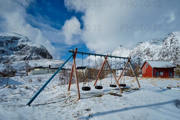 Children playground with swings made of car tires in winter