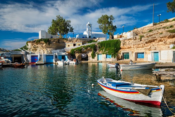 Fishing boats moored in crystal clear turquoise sea water in harbour in Greek fishing village of Mandrakia