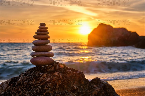 Cairn stack of stones pebbles cairn on the beach coast of the seaon sunset