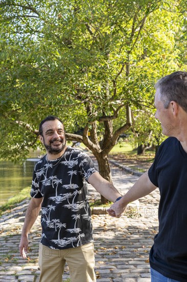 Gay man surprised and happy because his boyfriend holds his hand in public while they are walking in a lake. Coming out concept