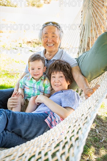 Chinese grandparents in hammock with mixed-race child