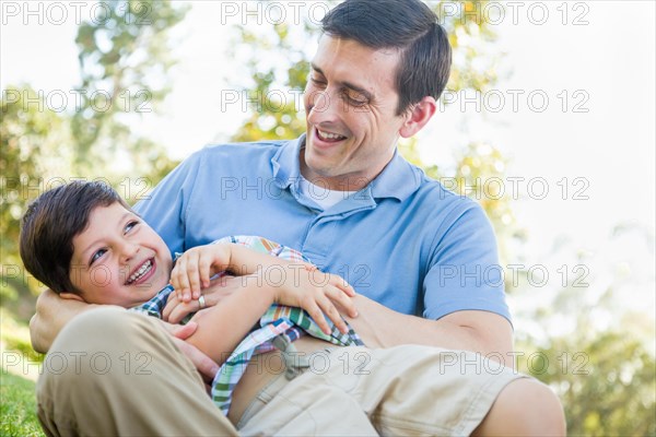 Loving young father tickling son in the park