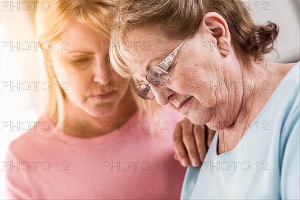 Young adult woman consoles sad senior adult female