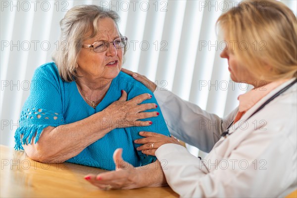 Senior adult woman talking with female doctor about sore shoulder