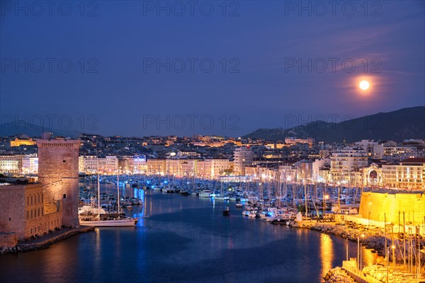 Marseille Old Port and Fort Saint-Jean illumintaed in night with moon. Marseille