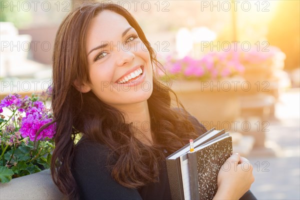 Portrait of pretty young female student carrying books on school campus