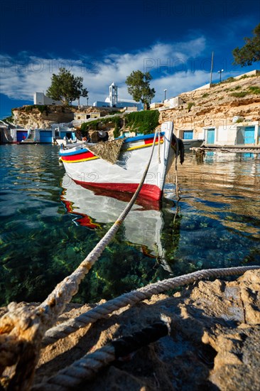 Fishing boats moored in crystal clear turquoise sea water in harbour in Greek fishing village of Mandrakia