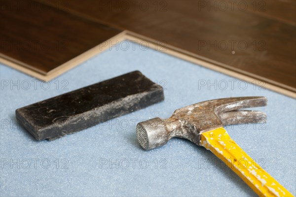 Hammer and block with new laminate flooring abstract