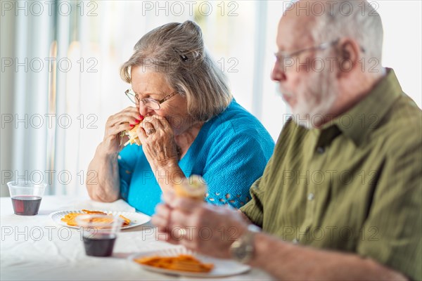 Senior adult couple enjoying sandwiches at table