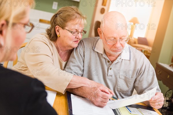 Senior adult couple going over documents in their home with agent at signing