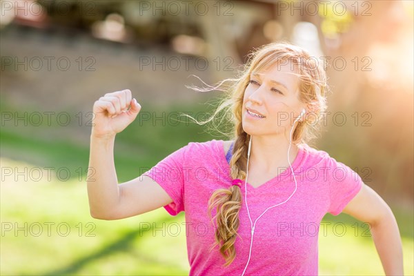 Young fit adult woman outdoors during workout listening to music with earphones