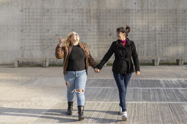 Latin lesbian couple looking at each other with affection walking hand in hand in the street