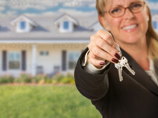 Real estate agent handing over new house keys with house behind
