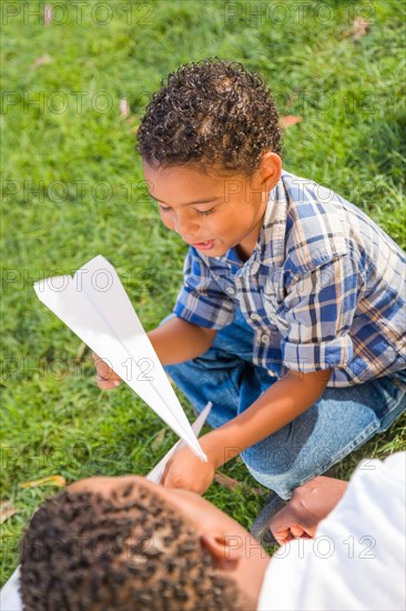 Happy african american father and mixed-race son playing with paper airplanes in the park