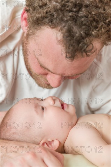 mixed-race chinese and caucasian baby boy laying in bed with his father