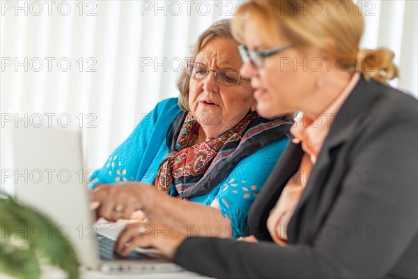 Woman helping senior adult lady on laptop computer