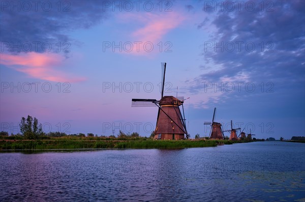 Netherlands rural lanscape with windmills at famous tourist site Kinderdijk in Holland in dusk with dramatic sky