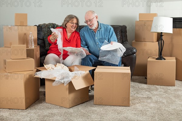 Senior adult couple packing or unpacking moving boxes