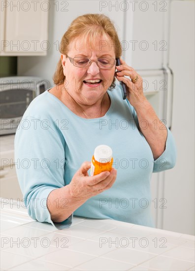 Senior adult woman on cell phone holding prescription bottle