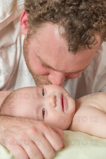 mixed-race chinese and caucasian baby boy laying in bed with his parents