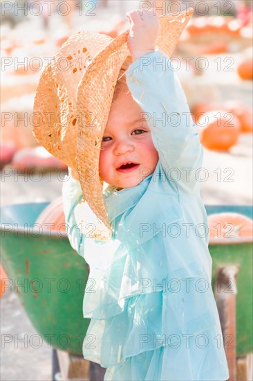 Adorable baby girl with cowboy hat in a country rustic setting at the pumpkin patch