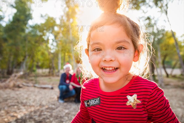 Cute mixed-race baby girl christmas portrait with family behind outdoors