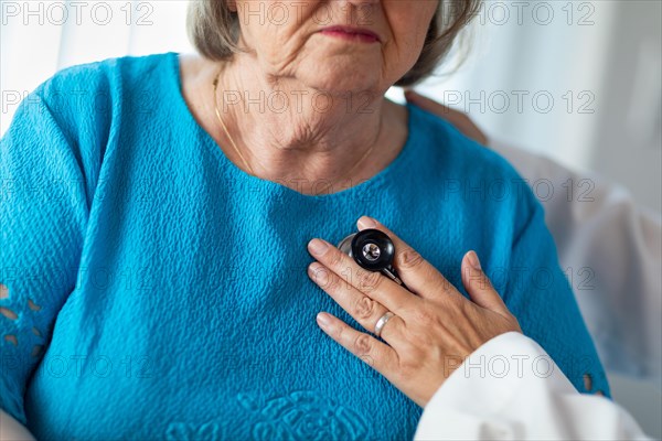 Female doctor checking the heart with stethoscope of senior adult woman