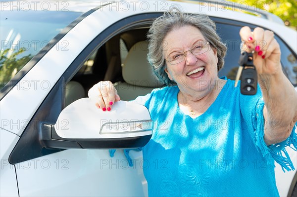 Happy senior woman with new car and keys