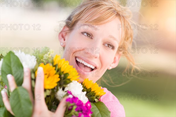 Outdoor portrait of an excited young adult brown eyed woman holding a bouquet of flowers