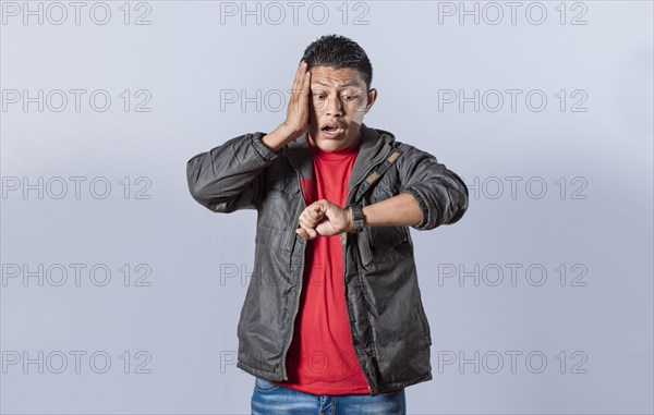 Young man in jacket looking at the watch time worried